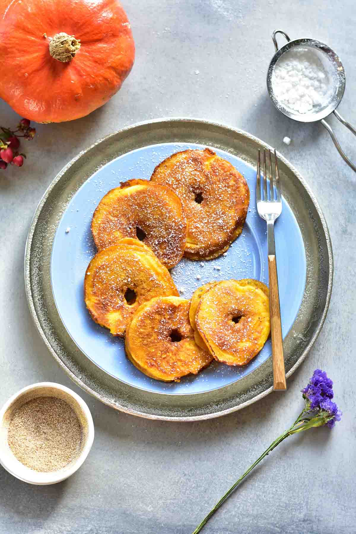 Pumpkin apple ring pancakes on a blue plate.
