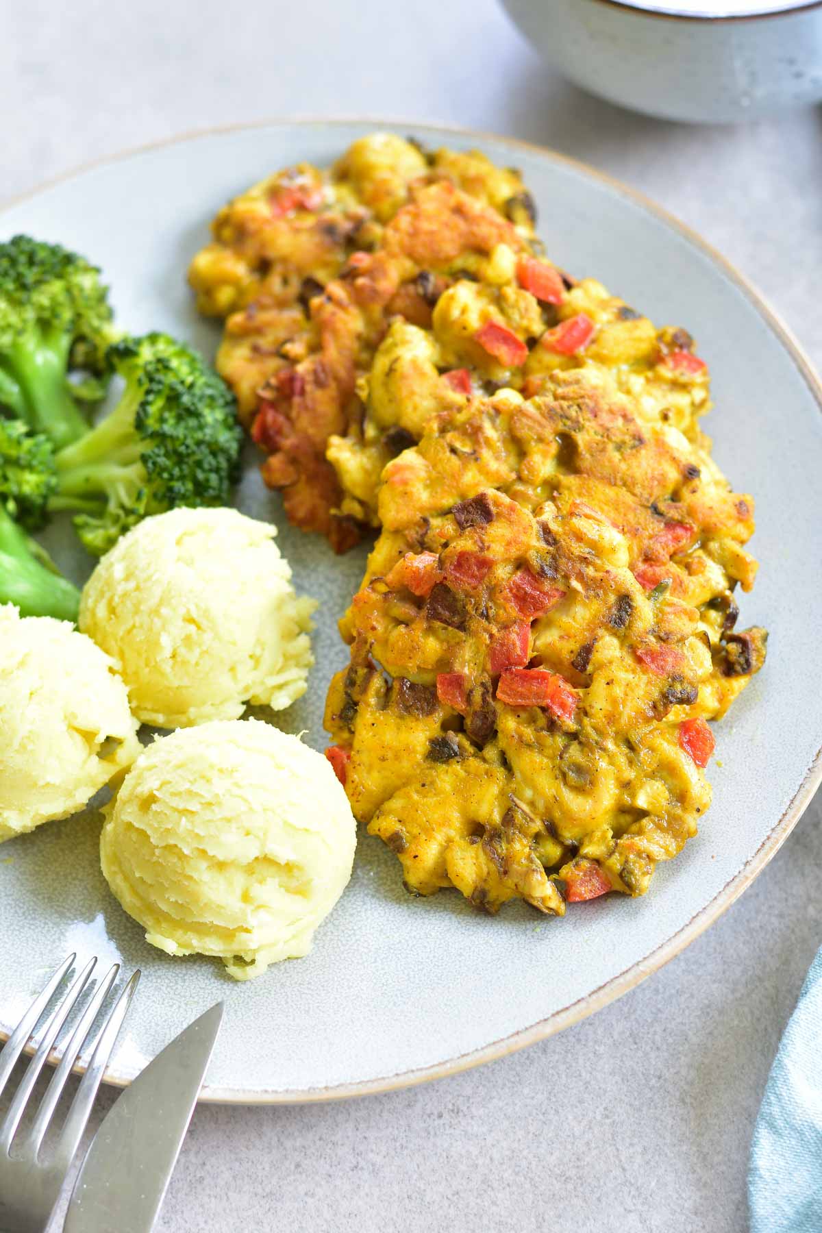 Curried chicken fritters with cremini mushrooms and bell paprika on a blue plate.