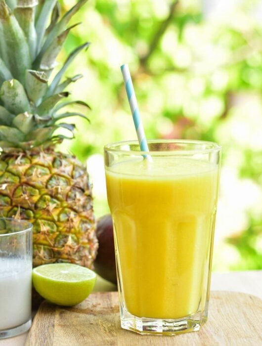 pineapple mango coconut smoothie in a glass on a wooden board