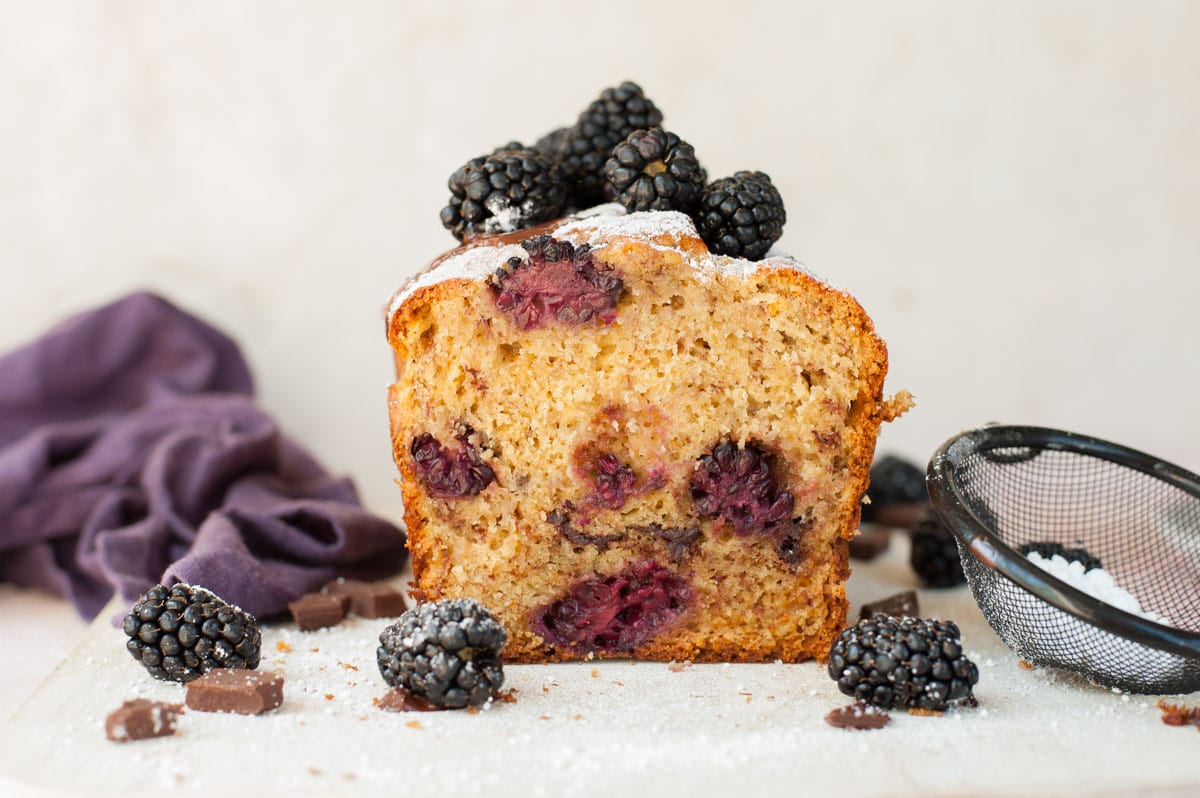 Blackberry banana bread cut in half on a wooden board.