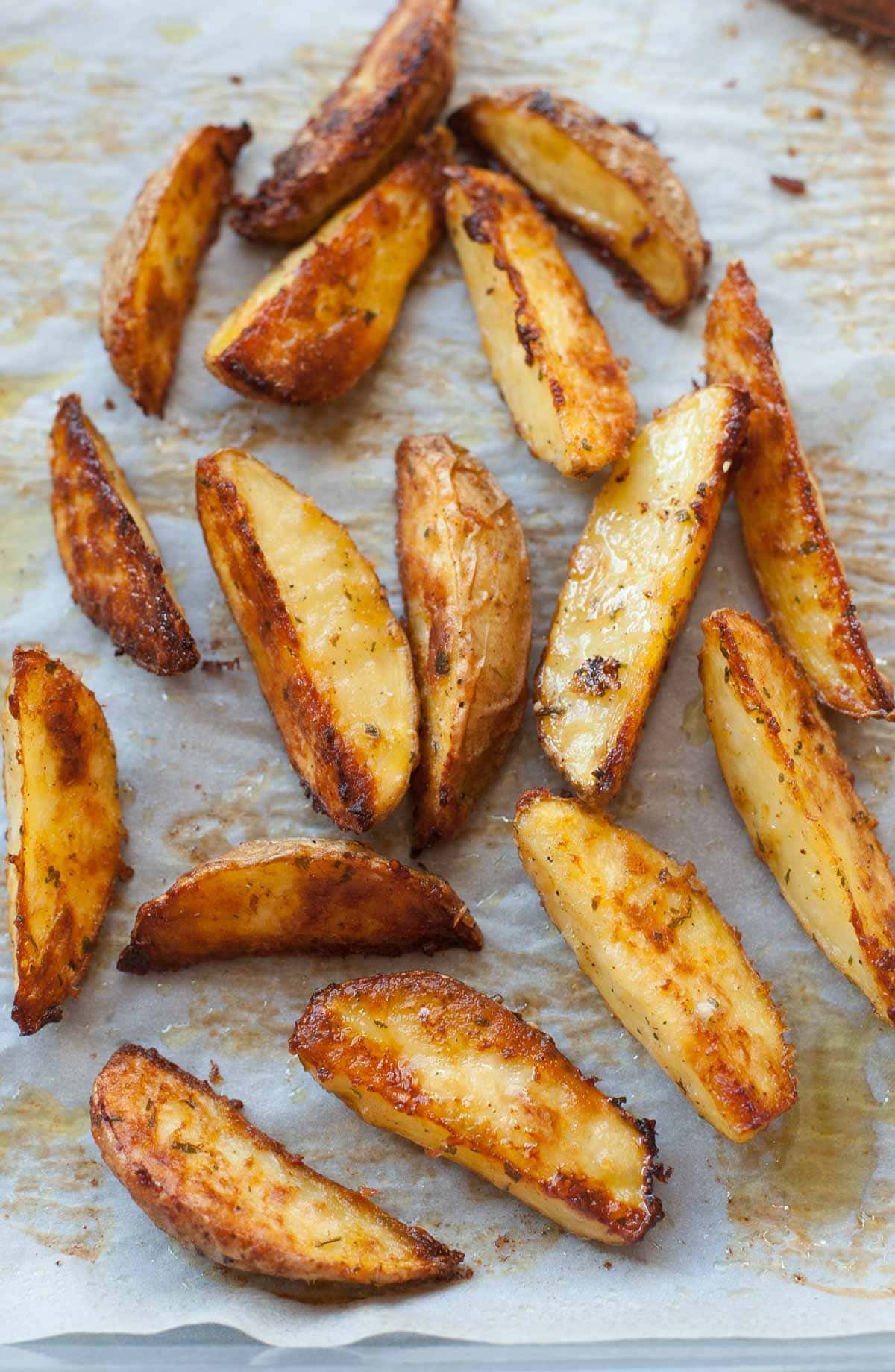 Baked Lemon, parmesan, parsley potato wedges on a parchment paper.