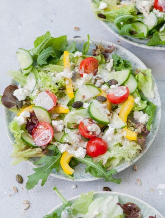 Salad with yogurt dressing on a green plate.