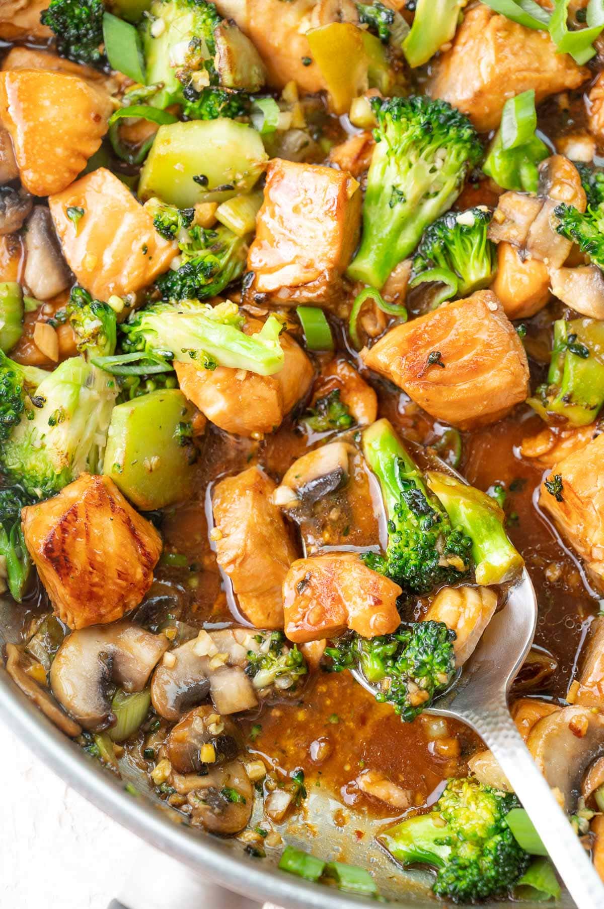 Salmon stir fry with broccoli and mushrooms in a frying pan.