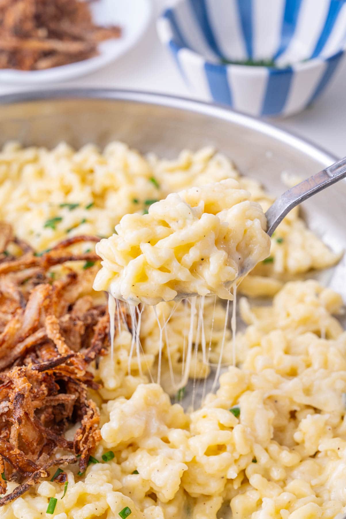 Käsespätzle on a spoon and in a frying pan.