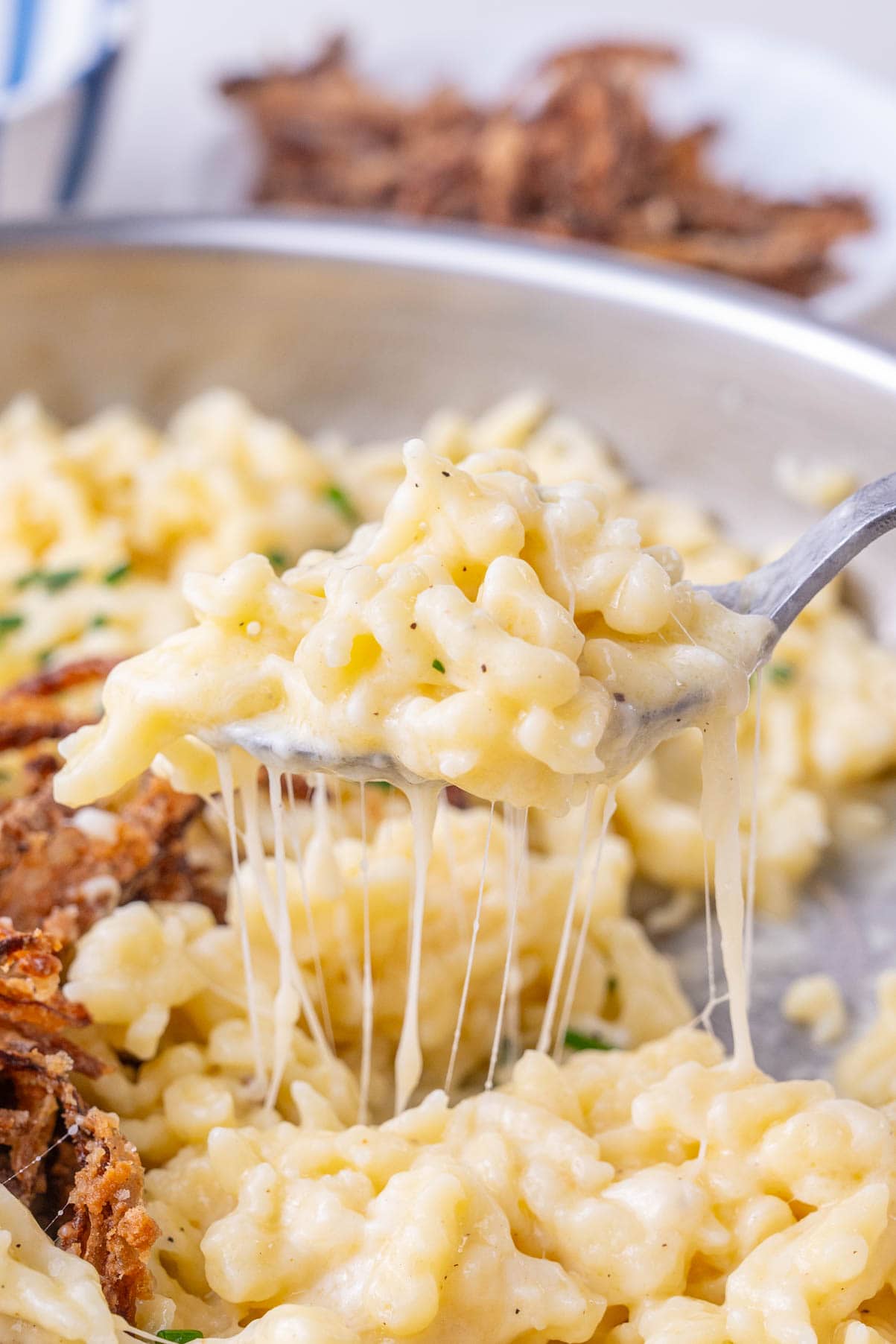 Käsespätzle in a frying pan and on a spoon.